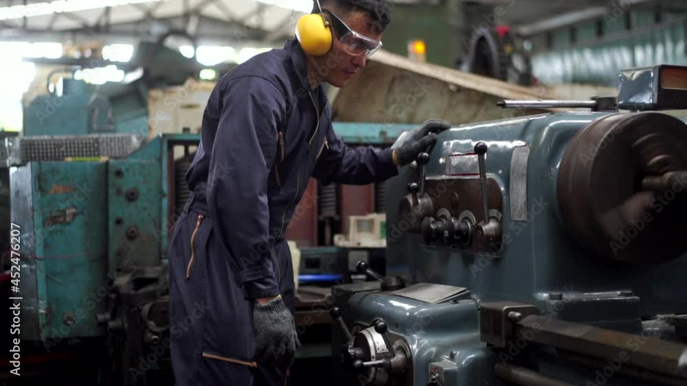 Professional Asian man Industry worker in safety ear muff working in machinery factory. Male labor foreman technician working with metal machine. Manufacturing factory and build construction concept Professional Asian man Industry worker in safety ear muff working in machinery factory. Male labor foreman technician working with metal machine. Manufacturing factory and build construction concept