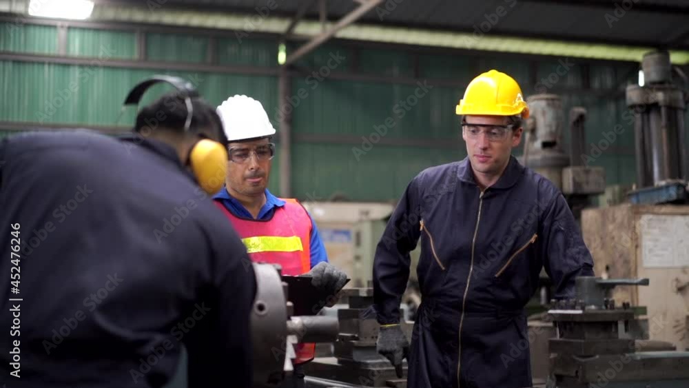 Group of Diversity man industry engineer and worker teamwork in safety helmet working together in factory. Male foreman technician introduce factory department and metal machine work to senior manager Group of Diversity man industry engineer and worker teamwork in safety helmet working together in factory. Male foreman technician introduce factory department and metal machine work to senior manager