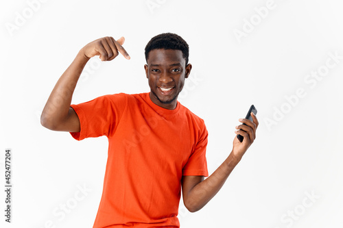 Cheerful man of african appearance with a phone in his hands gesturing with a finger light background