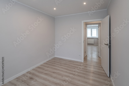 Contemporary interior of empty room in renovated apartment. White walls. Light laminate floor. Nobody.
