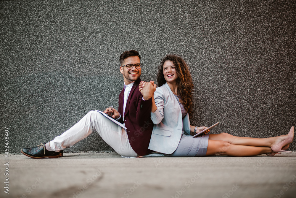 Young business people sitting down in front of a modern office building Young business people sitting down in front of a modern office building