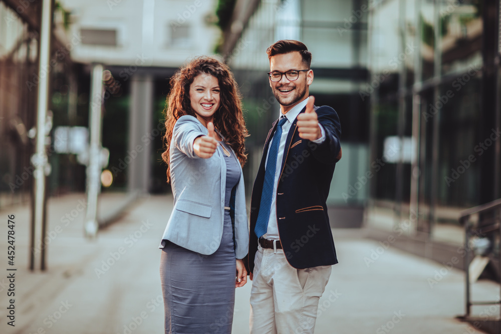 Business woman and business man holding thumbs up outdoor