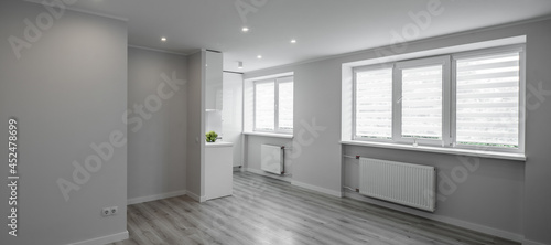 Modern light interior of renovated studio apartment without furniture in scandinavian style. Empty living room and white kitchen.