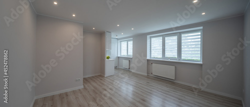 Studio apartment after renovation. Modern light interior in scandinavian style. White kitchen. Parquet floor. Panorama view.