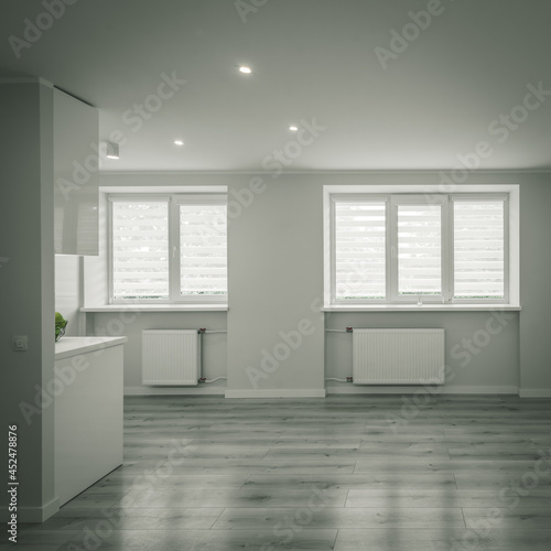 Modern bright interior of luxury studio apartment after renovation. Spacious living room. White walls. Beige parquet.