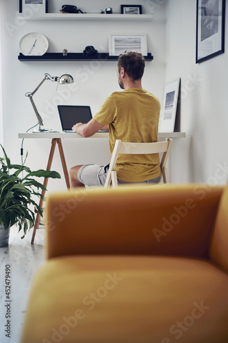 Adult caucasian man working on a laptop at home.