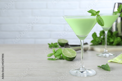 Delicious mint liqueur with green leaves on white wooden table. Space for text