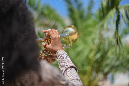 Rear close view of an african woman playing the trumpet in the city outside
