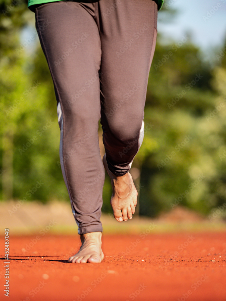 Running female bare feet in long leggings. Mature woman runs Stock