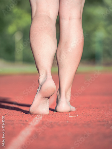 Woman running on stadium track during sunny morning