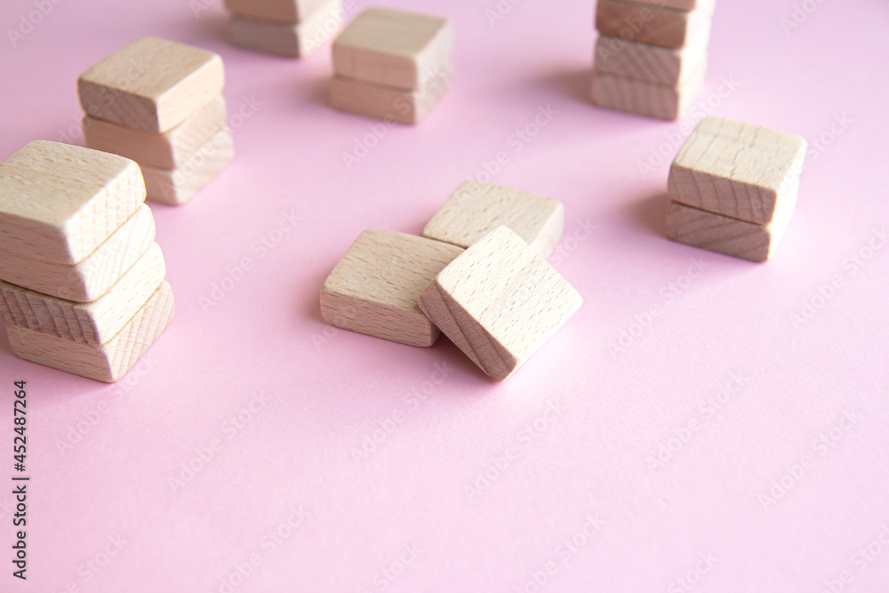 Set of stacks of wooden cubes on a pink background. Concept of balance, team building