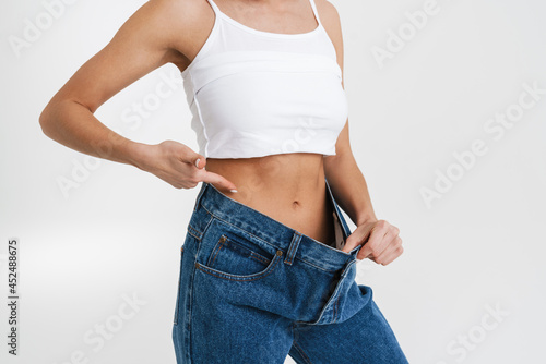 European woman pointing finger at her waist while posing in big jeans