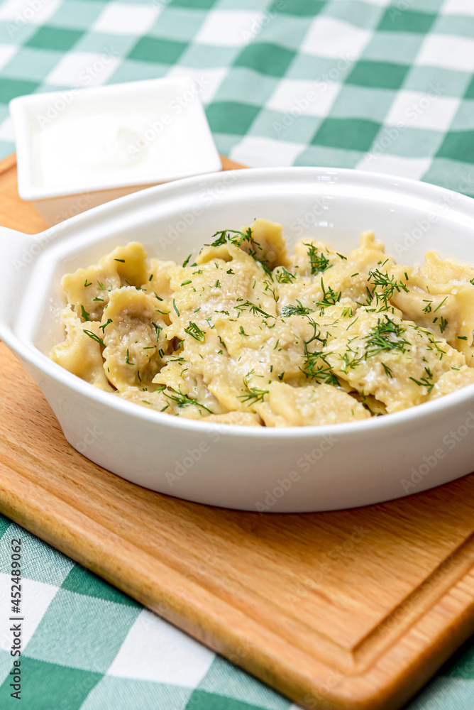 Italian ravioli with spinach and cheese close-up, rustic style. Served in a white pan over rustic wooden board Italian ravioli with spinach and cheese close-up, rustic style. Served in a white pan over rustic wooden board