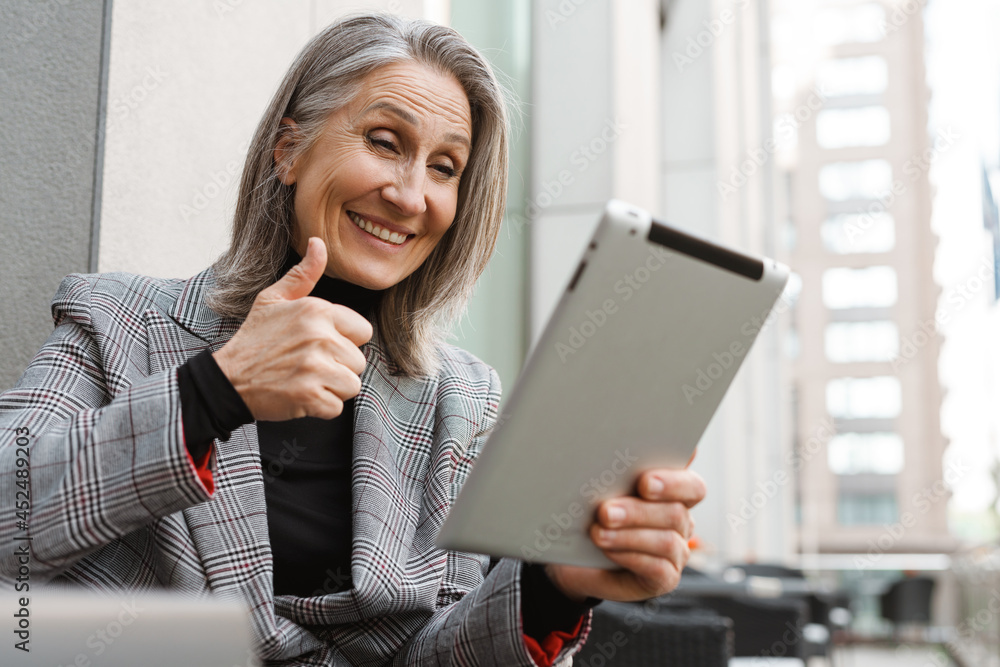 Grey white senior woman using tablet computer while sitting in cafe Grey white senior woman using tablet computer while sitting in cafe