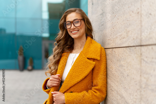 Business woman dressed yellow coat standing outdoors corporative building background