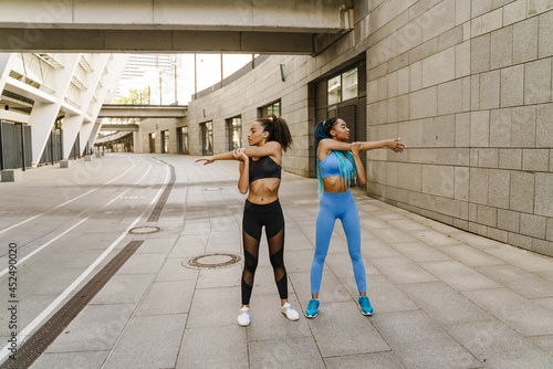 Two smiling young african fitness women exercising