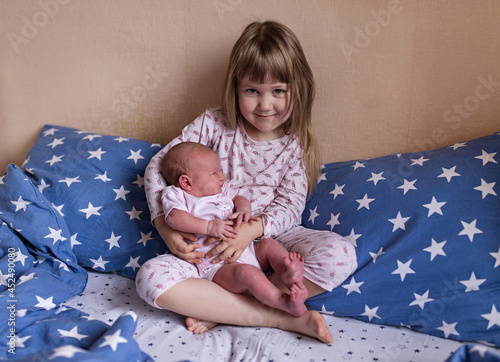 Two girls sisters in pajamas together on the bed. Older and younger sisters.
