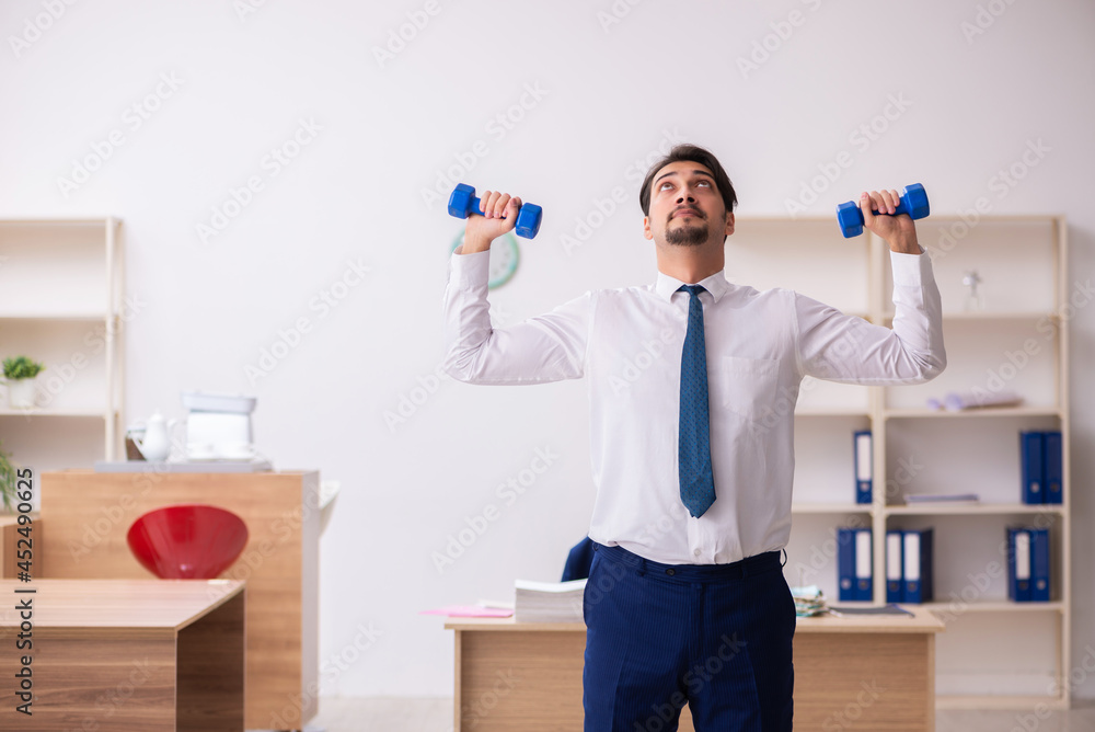 Young male employee doing sport exercises during break Young male employee doing sport exercises during break