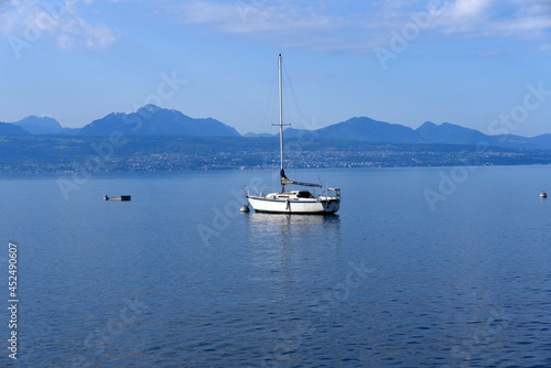 Lake Geneva at Lausanne on a cloudy summer day with sailing yacht in the foreground. Photo taken August 11th, 2021, Lausanne, Switzerland.