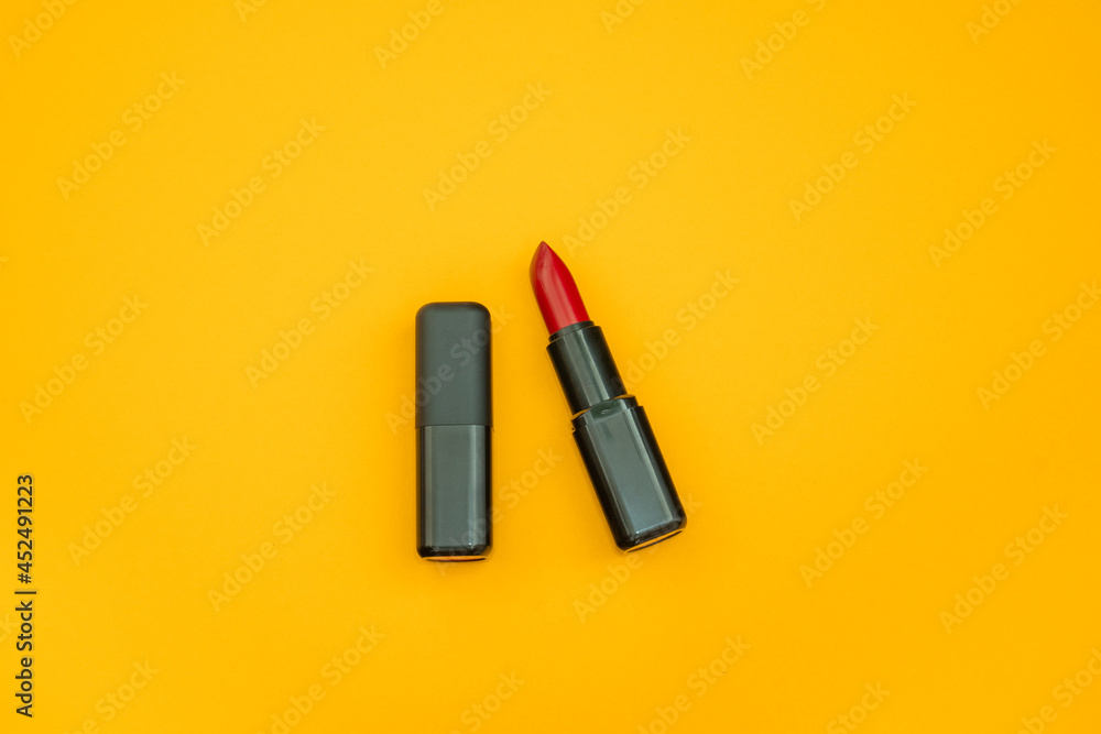 Naklejka premium Fashion cosmetics photo of red lipsticks in a black packaging on a yellow background 
