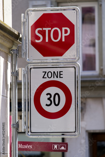 Traffic signs stop and zone 30 at City of Nyon on a sunny summer day. Photo taken August 11th, 2021, Nyon, Switzerland.