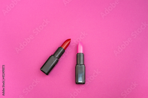 Fashion cosmetics photo of red and pink lipsticks on a pink background 