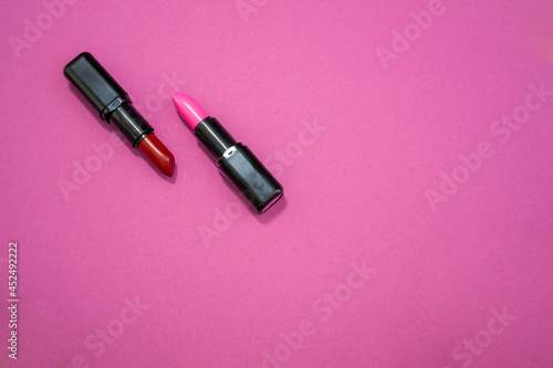 Fashion cosmetics photo of red and pink lipsticks on a pink background 