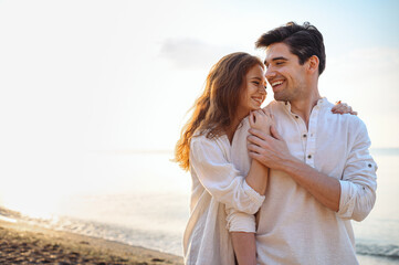 Smiling young couple two friends family man woman 20s in casual clothes hug girlfriend put head on boyfriend shoulder at sunrise over sea sand beach ocean outdoor seaside in summer day sunset evening.