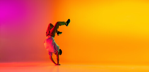Flyer with young stylish man, break dancing dancer training in casual clothes isolated over gradient pink yellow background at dance hall in neon light.