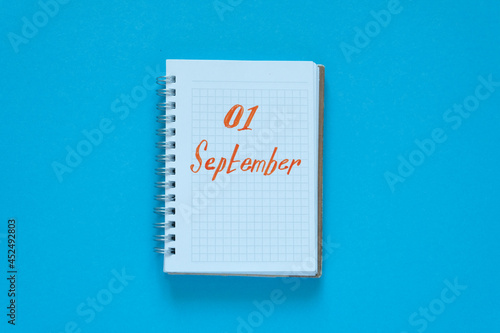 Flat lay. Blue background. In the center is a notebook with the text "September 1". Knowledge day, study, school, college.