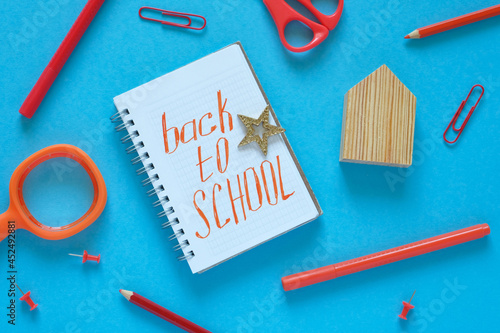 Flat lay. Blue background. In the center is a notebook with the text "Back to School". Stationery lies around. Knowledge day, study, school, college.