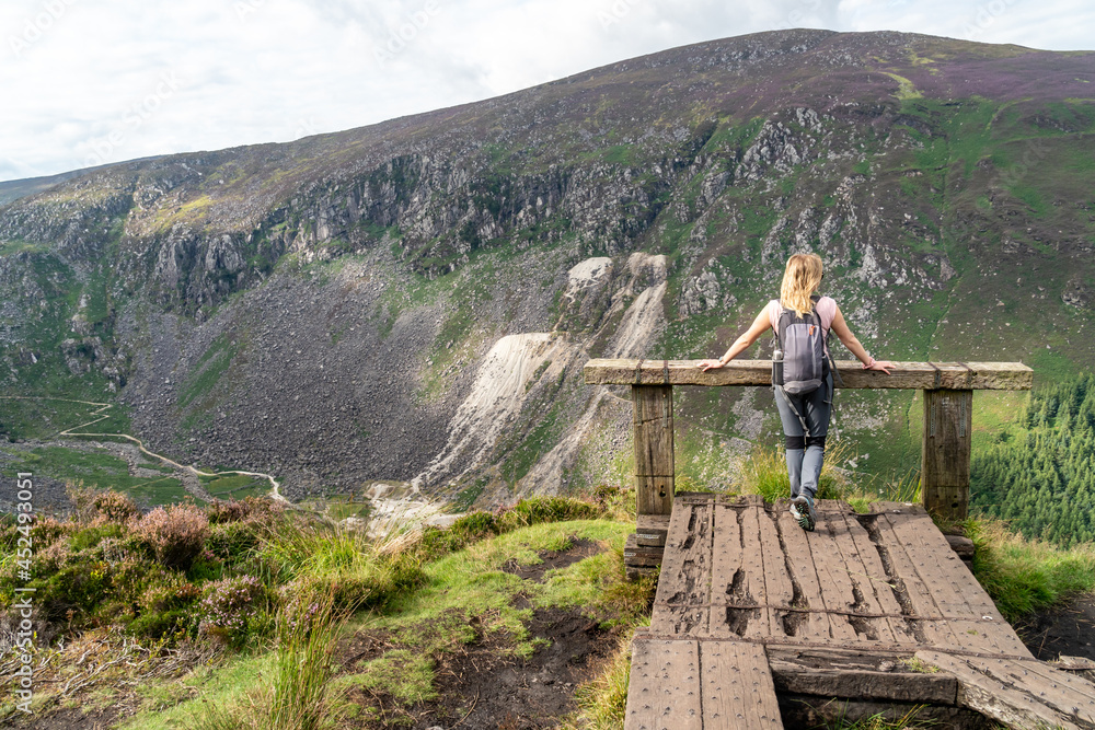 Girl resting on the hill at the Glendalough Valley. Panoramic idyllic view. County Wicklow Upper lake from miners way, Glenealo valley, Wicklow way, County Wicklow, Ireland.