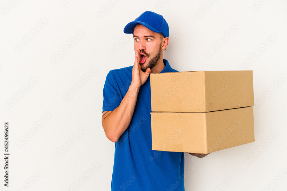 Young caucasian delivery man with tattoos isolated on white background is saying a secret hot braking news and looking aside Young caucasian delivery man with tattoos isolated on white background is saying a secret hot braking news and looking aside