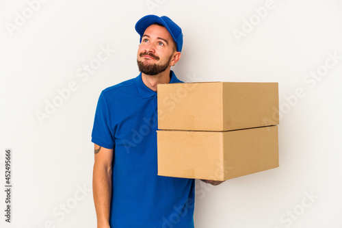 Young caucasian delivery man with tattoos isolated on white background dreaming of achieving goals and purposes