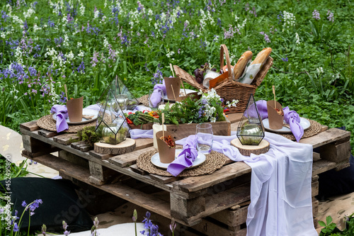 Rustic picnic table with food in a spring meadow for a woodland naming ceremony.