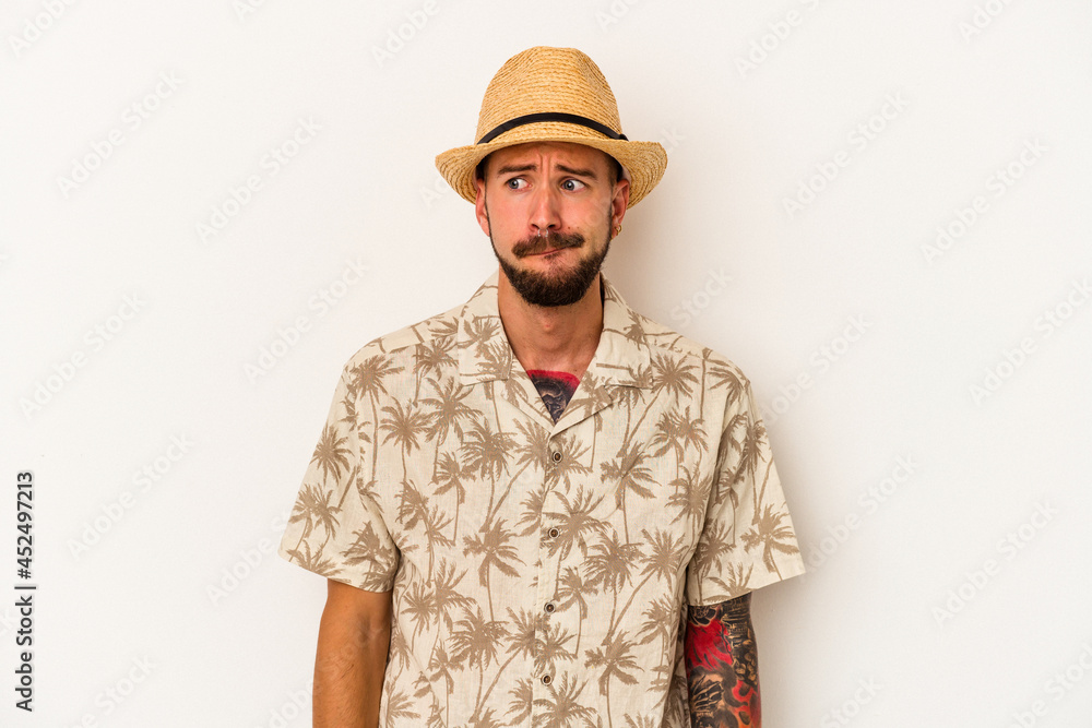 Young caucasian man with tattoos wearing summer clothes isolated on white background confused, feels doubtful and unsure. Young caucasian man with tattoos wearing summer clothes isolated on white background confused, feels doubtful and unsure.