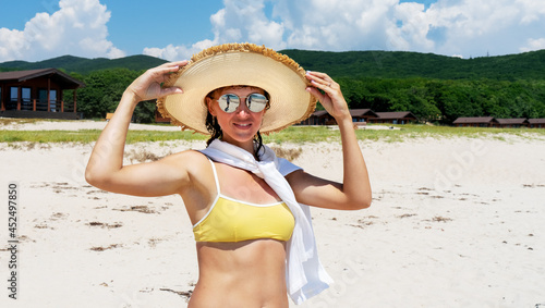 Portrait of happy tanned travel woman elegant hat and sunglasses posing at exotic beach coast