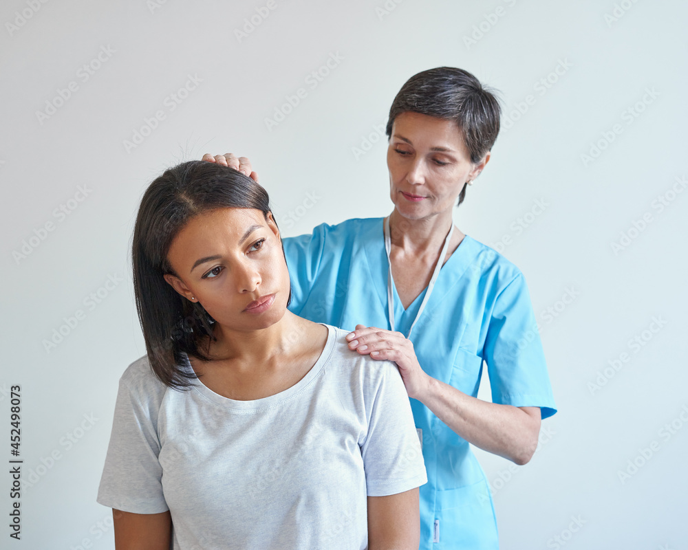 Office syndrome treatment. Professional middle-aged female neurologist doctor examining neck and shoulder of young upset african woman patient during visit in medical clinic. Osteopathy concept - obrazy, fototapety, plakaty 