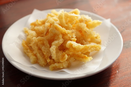 Angle view of Deep fried fish maw with a white dish on wood table.