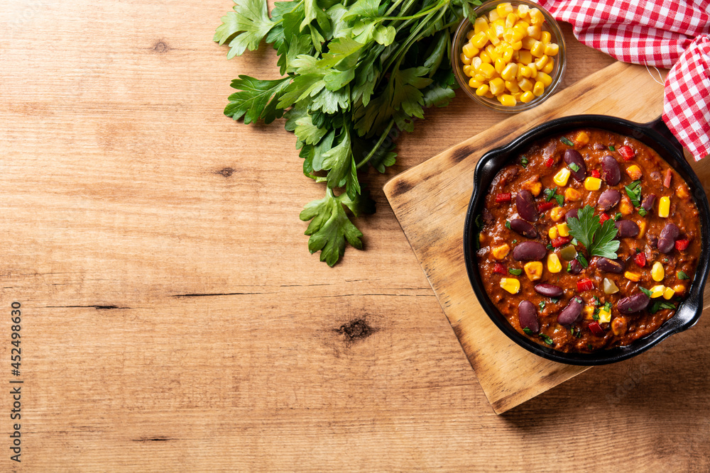 Traditional mexican tex mex chili con carne in iron pan on wooden table. Top view. Copy space
