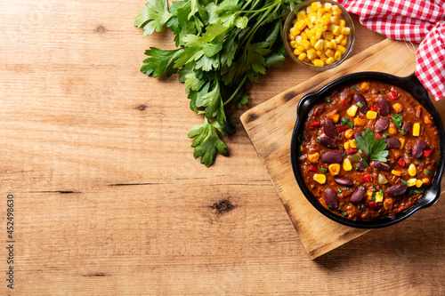 Traditional mexican tex mex chili con carne in iron pan on wooden table. Top view. Copy space