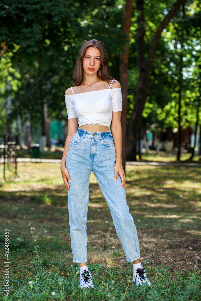Young beautiful girl in blue jeans posing in a summer park Young beautiful girl in blue jeans posing in a summer park