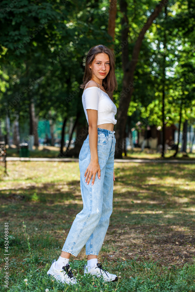 Young beautiful girl in blue jeans posing in a summer park Young beautiful girl in blue jeans posing in a summer park