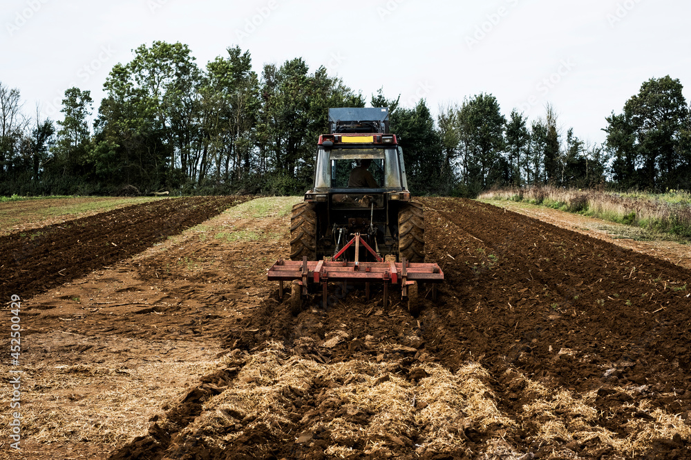 Rear view of tractor plowing a field on a farm. Rear view of tractor plowing a field on a farm.