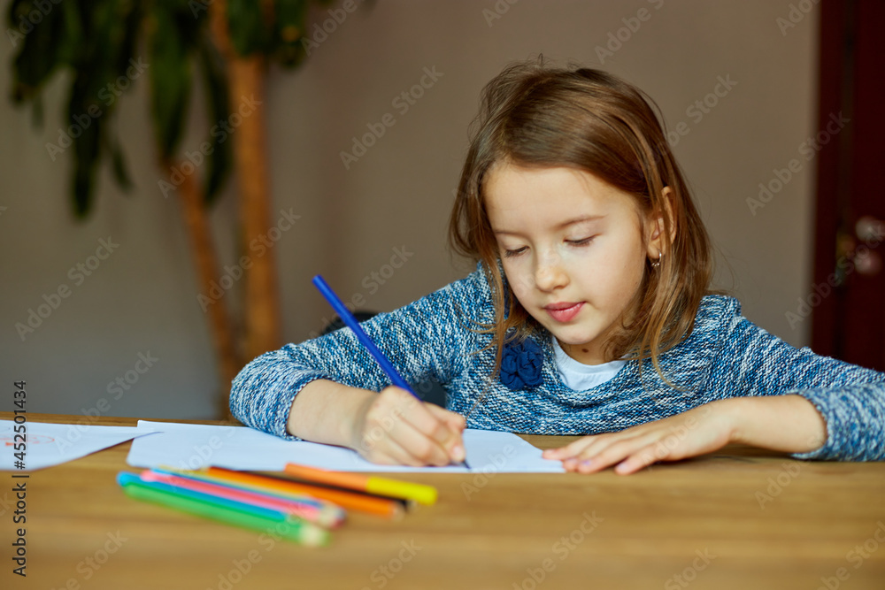 School girl drawing and writing a picture with crayons, using colored pencils School girl drawing and writing a picture with crayons, using colored pencils