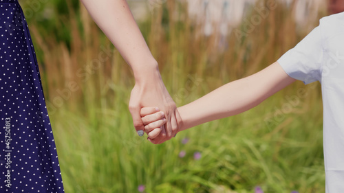 Close up of mother holding hand of son on spring day outdoors