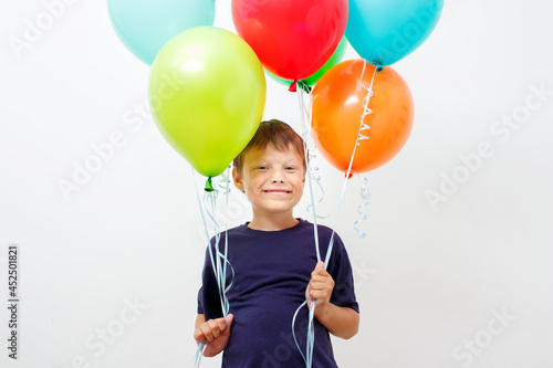 Happy eight year old boy with an armful of bright colorfull balloons celebrates birthday.