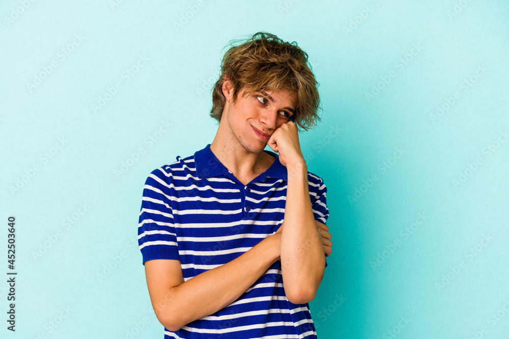Young caucasian man with make up isolated on blue background who feels sad and pensive, looking at copy space. Young caucasian man with make up isolated on blue background who feels sad and pensive, looking at copy space.