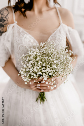 The bride in a white dress with a bouquet of gypsophila
