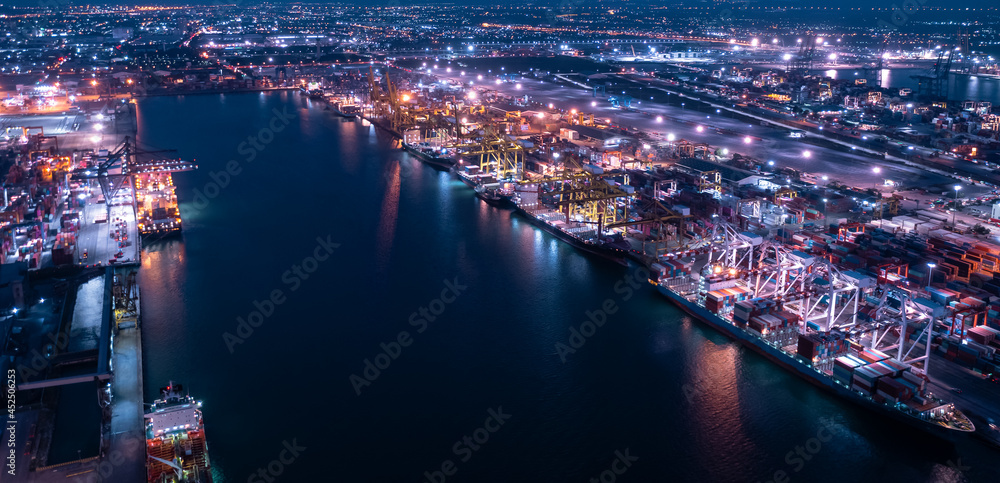 Containers ship and ports logistic freight load unloading by crane industry and business service shipping import export goods transportation of international at night scene aerial view